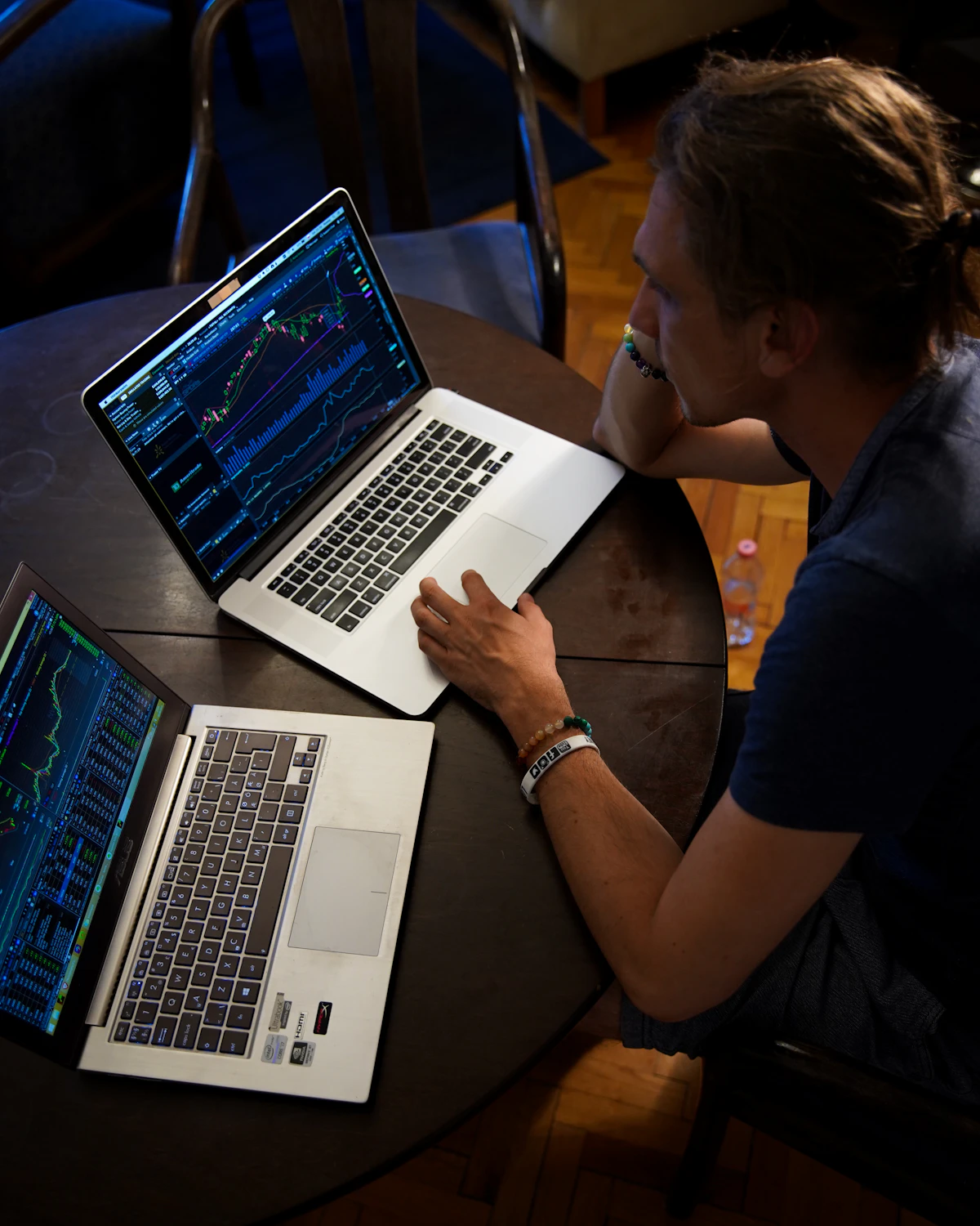 An asset manager reviewing market charts on two laptops