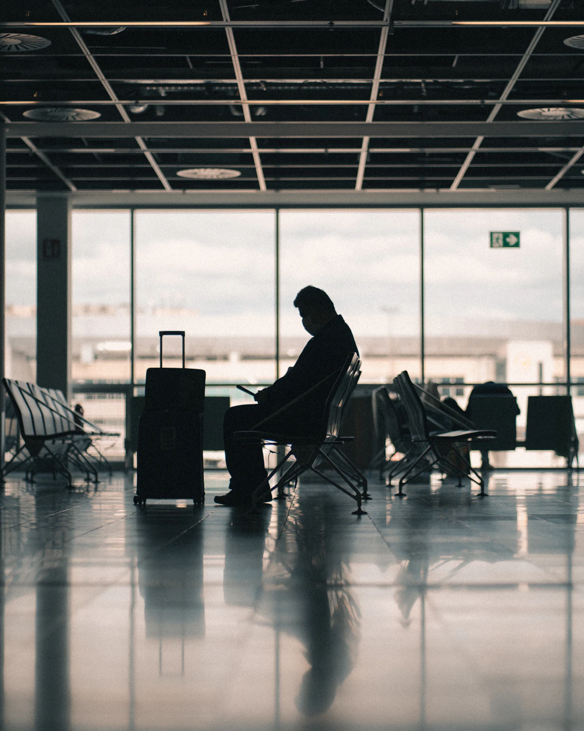 A traveller with a suitcase checking their phone in an airport terminal
